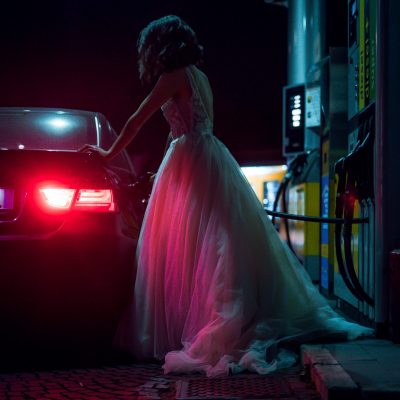 woman-in-white-dress-fueling-car-during-night-3888557